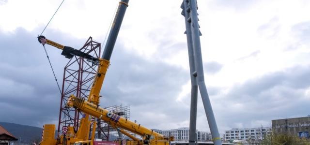 orangefarbiger Kran und weißer Pylon in Y-Form
