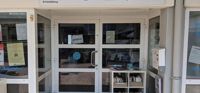 Blick auf eine Glastür mit einem kleinen Bücherregal davor.