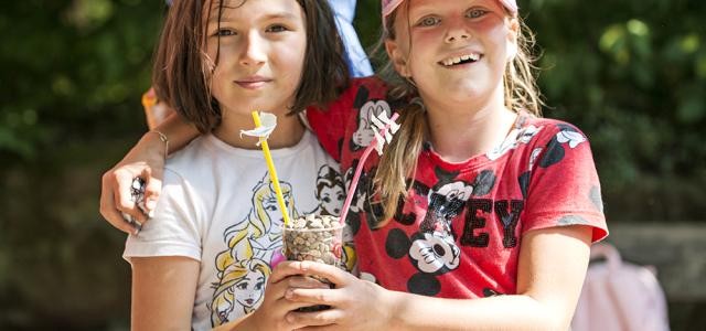 Zwei Kinder mit einem Becher in der Hand
