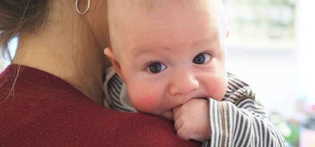 Ein Baby ist auf dem Arm einer Frau und schaut über ihre Schulter