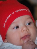 Baby mit Heidelberg-Mützchen (Foto: Kristina Wetzel) Ein Baby trägt eine rote Mütze mit der Aufschrift "Gut behütet in Heidelberg" und lächelt (Foto: Kristina Wetzel)