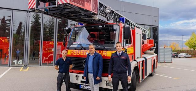 Drei Personen stehen vor einem Feuerwehrauto