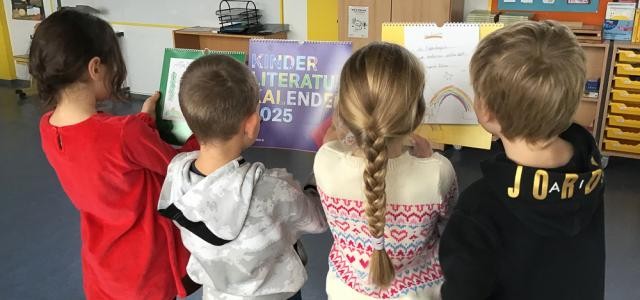 Vier Kinder in Rückenansicht sehen sich mehrere Kalender an