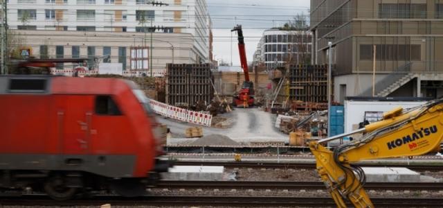 Bild der Baustelle der Gneisenaustraße, während davor ein Zug auf der Strecke fährt.