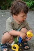 Kleines Kind sitzt in der Hocke und spielt mit einem Spielzeugbagger (Foto: Kristina Wetzel)