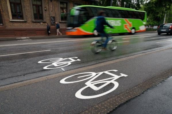 Auf einer stark befahrenen Straße ist der Fahrradweg mit dem Piktogramm im Fokus. 
