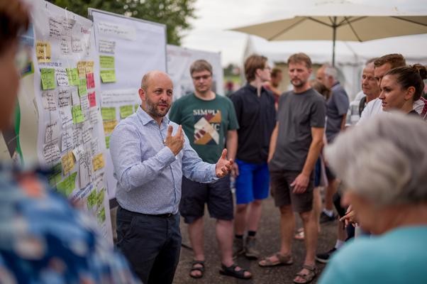 Moritz Bellers vom Stadtplanungsamt der Stadt Heidelberg erläutert die Pläne der Verwaltung und kommt dabei mit Bürgerinnen und Bürgern ins Gespräch. (Foto: Tobias Dittmer) Mehrere Menschen stehen um ein Plakat herum, eine Person erklärt etwas