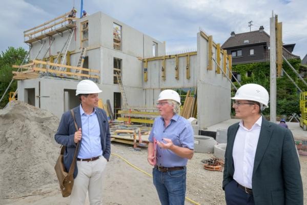 Auf der Baustelle im Wieblinger Weg schreiten die Arbeiten zügig voran. Nach dem Spatenstich im April sind schon die ersten Gebäude in die Höhe gewachsen. Erster Bürgermeister Jürgen Odszuck (v.l.), Projektleiter Wolfgang Hofmann und GGH-Geschäftsführer Peter Bresinski beim Vor-Ort-Besuch. (Foto:Philipp Rothe) Drei Menschen mit weißen Helmen auf dem Kopf stehen vor einem Gebäude, das gerade gebaut wird