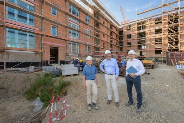 Rund 600 Wohnungen sollen auf dem Hospital-Areal entstehen. Über den Fortschritt der Arbeiten informierte Projektleiter Wolfgang Hofmann (v.l.) Ersten Bürgermeister Jürgen Odszuck und GGH-Geschäftsführer Peter Bresinski. (Foto: Philipp Rothe) Drei Menschen mit weißen Helmen auf dem Kopf stehen vor einem Gebäude, das gerade gebaut wird