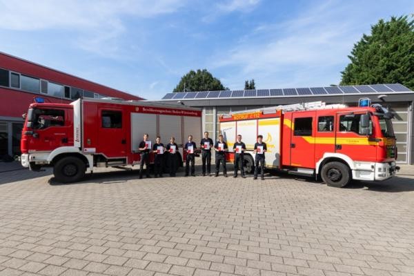 Gruppenbild Grundlehrgang Gruppenbild zum Prüfungsende vor zwei Feuerwehrfahrzeugen