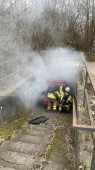 PKW-Brand zwei Feuerwehrmänner arbeiten an einem rauchenden PKW