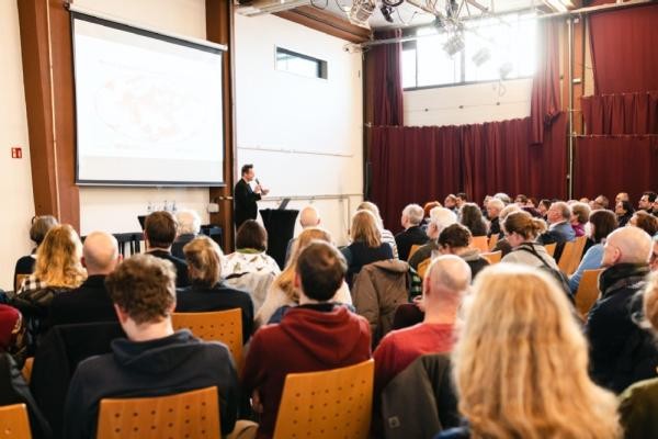 Alle Materialien zu den Veranstaltungen der Reihe „Stadtentwicklung im Dialog“ gibt es unter www.heidelberg.de. Zuletzt hatte die Stadt zum Themenschwerpunkt „Mehr Grün in der Stadt“ eingeladen. Dort referierte unter anderem Landschaftsarchitekt Stephan Lenzen aus Köln. (Foto: Mayer) Ein Mann hält einen Vorttag vor eine Gruppe Menschen.