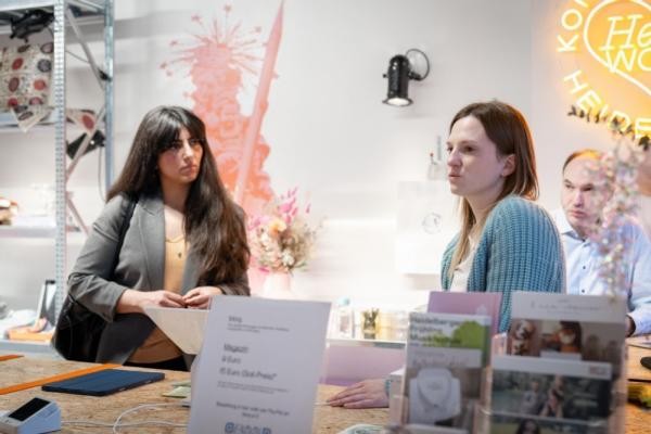 Im Konzeptladen „Heartwork“ in der Unteren Straße in der Altstadt bieten Heidelberger Unternehmerinnen und Unternehmer ihre Produkte „Design made in Heidelberg“ an. (Foto: Buck) Zwei Frauen und ein Mann um einen Tisch. Auf dem Tisch sieht man Flyer und andere Sachen.
