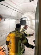 Im Rahmen der Übung im Schlossbergtunnel der Feuerwehr Heidelberg ging es auch darum, den Tunnel zu begehen und somit wichtige Erkenntnisse für den Ernstfall zu gewinnen. (Foto: Feuerwehr Heidelberg) Zwei Männer in Feuerwehruniform in einem ausgeleuchteten kleinen Tunnel.