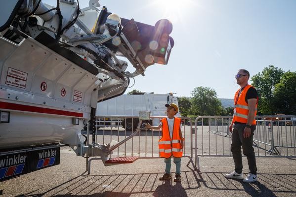 Je größer die Maschine, desto größer der Spaß: Eine Mülltonne selbst leeren zu dürfen, sorgt für leuchtende Kinderaugen. (Foto: Stadt Heidelberg) Ein Junge in Warnweste bedient einen Abfallwagen.