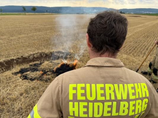 Ein Feuerwehrmann beobachtet, wie sich das Feuer im Acker langsam ausbreitet