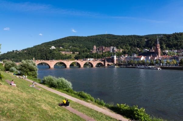 Der Sommer in Heidelberg bietet vielfältige Möglichkeiten – ob Kultur, Sport, Naturerlebnisse, Freizeitangebote – es gibt Programm für Jung und Alt. (Foto: Steffen Diemer) Am Heidelberger Neckarufer machen es sich mehrere Besucher und Besucherinnen in der Nähe der alten Brücke gemütlich.