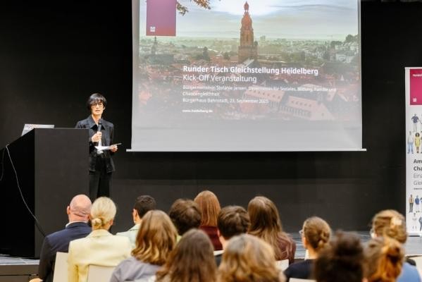 Will ein starkes Frauennetzwerk knüpfen: Bürgermeisterin Stefanie Jansen bei der Auftaktveranstaltung im Bürgerhaus Bahnstadt. (Foto: Joe Pohl) Bürgermeisterin Stefanie Jansen steht auf dem Podium im Bürgerhaus der Bahnstadt. Hinter ihr ist die die Begrüßungsfolie der Präsentation zu sehen.