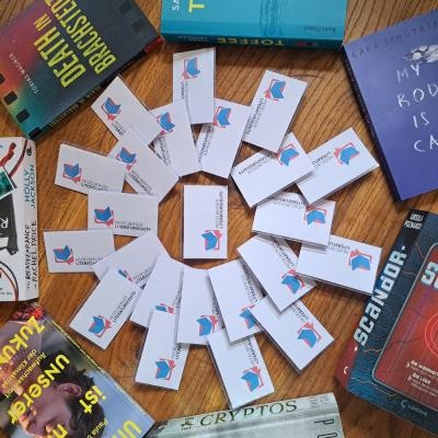 Die Heidelberger Literaturscouts freuen sich über weitere Mitstreiterinnen und Mitstreiter. (Foto: Sophie von Zadow) Zu sehen sind Flyer der Literatourscouts die auf einem Tisch zu einem mandalaähnlichem Muster zusammengelegt sind und von Büchern umrahmt werden.