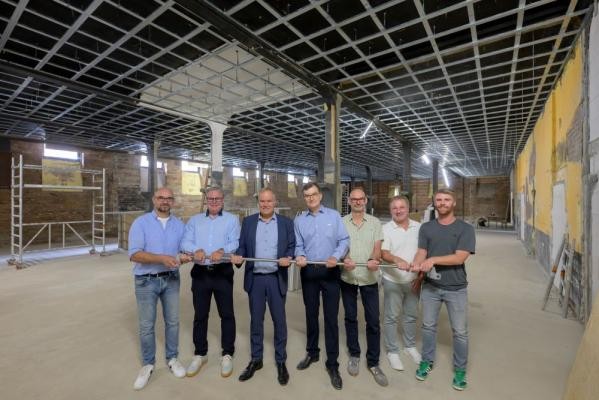 In der „Sportschicht“ in den Räumen der früheren Nachtschicht wird künftig unter anderem auch geturnt: Beim Baustellenbesuch griffen Ralph Fülop (Sportkreis; von links), Gert Bartmann (Sportamt), Oberbürgermeister Eckart Würzner, Bernhard Hammes (Landfried), Martin Brandel (Heidelberger TV), Thomas Jung (Sportamt) und Tim Posawatz (Heidelberger TV) bereits zur Reckstange. (Philipp Rothe) Sieben Personen stehen in einer Halle der "künftigen Sportschicht".