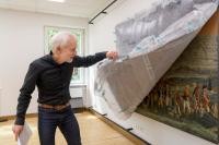 MTC-Leiter Dr. Uwe Wetzel blickt hinter die Kulissen: Die historische Wandtapete der Tapetenmanufaktur Zuber zeigt Szenen aus dem amerikanischen Unabhängigkeitskrieg. Ein Original befand sich ehemals auf dem Campbell-Gelände, ein Ausschnitt davon ist im MTC ausgestellt. Foto von älterer Mann, der hinter die Kulissen blickt