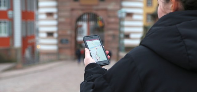 Frau hält Handy mit der "MeinHeidelberg"- App in der Hand