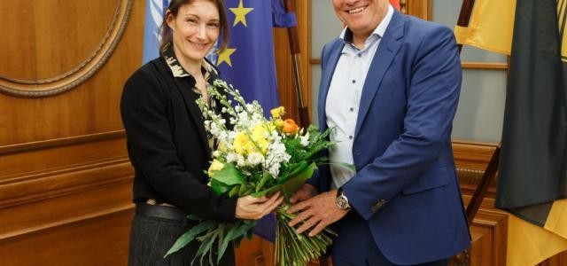 Oberbürgermeister Eckart Würzner und Bernadette Sonnenbichler halten zusammen einen Blumenstrauß und lächeln.