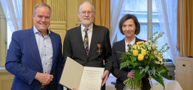 Oberbürgermeister Eckart Würzner, ein Mann mit Urkunde und eine Fraue mit Blumenstrauß sind zu sehen.