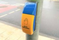 Viele Ampeln sind in Heidelberg mit einem akustischen Signal für Blinde und Sehbehinderte ausgestattet. An diesen Ampeln ist ein Taster angebracht, welcher zudem bei Grün vibriert. (Foto: Stadt Heidelberg) blau-gelber Ampelknopf mit Schriftzug "Bitte berühren."