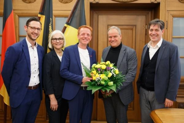 Oberbürgermeister Eckart Würzner begrüßte Marc Tell Feltl (3.v.r.), den Nachfolger von Harald Heußer, Leiter des Hochbauamts, am Donnerstag, 3. April 2025, im Rathaus. (Foto: Stadt Heidelberg) Gruppenfoto von vier Männern, darunter Oberbürgermister Eckart Würzner und einer Frau. In der Mitte hält ein Mann einen Blumenstrauß.