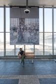 Eine Fotoausstellung im Heidelberger Hauptbahnhof ist eines der Projekte aus dem Verfügungsfonds der "Mittendrinnenstadt". (Foto: Buck) Ein Mann sitzt auf einer Bank unter einer riesigen Fotografie.