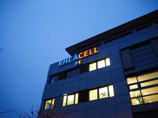 Der zweite Standort von RHEACELL im Pfaffengrund. (Foto: RHEACELL) Ein Gebäude vor einem dämmernden Himmel, das Firmenlogo ist an der Fassade befestigt und leuchtet.