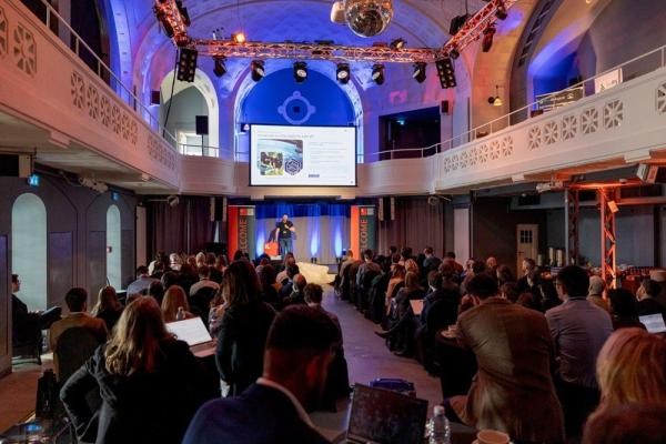 Die Veranstaltung "Genesis 26" fand im Frauenbad Heidelberg statt. (Foto: InnovationLab, Lukas Adler) Blick in das Innere des Heidelberger Frauenbads, wo Menschen in Reihen sitzen und auf eine Bühne mit Sprecher schauen.