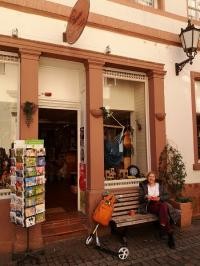 Eine Station bei den Touren ist beispielsweise der Eine-Welt-Laden. (Foto: Stadt Heidelberg) Eine Frau sitzt auf einer Bank vor dem Eine-Welt-Laden.