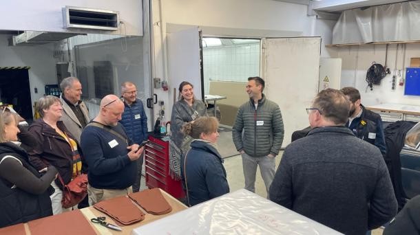 In der Sattlerei und Polsterei Waskey wurde die Werkstatt besichtigt. (Foto: Stadt Heidelberg) Eine Gruppe von Menschen steht in einer Werkstatt.
