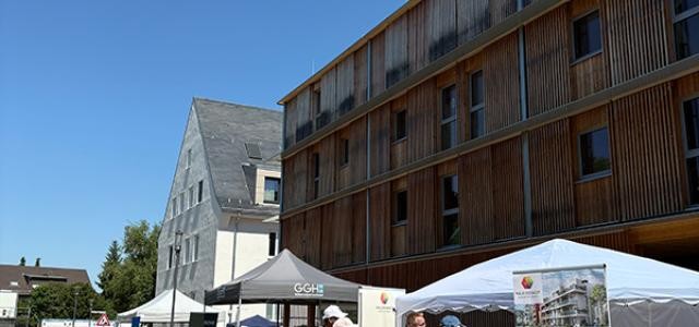 Einige Menschen stehen und flanieren vor Ständen der verschiedener Stadtentwicklungsunternehmen.