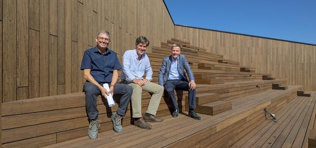 Drei Männer sitzen auf einer holzvertäfelten Treppe auf dem Dach des Congress Centers.