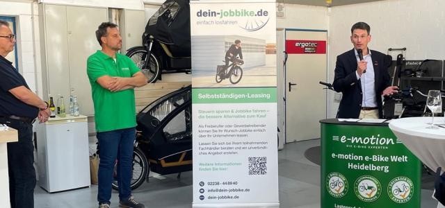Man sieht einen Redner und zwei zuhörende Männer beim Afterwork-Event.