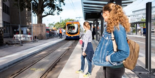 Zwei junge Frauen warten auf eine Straßenbahn am HBF Heidelberg