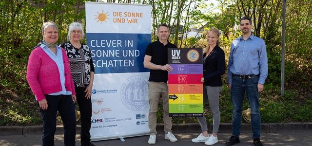 Fünf Personen stehen vor einem Aufsteller mit der Aufschrift "Clever in Sonne und Schatten".