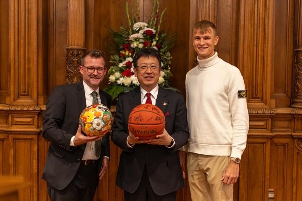 Heidelberg und Kumamoto planen regelmäßige Austausche im Jugendsport, beginnend vor allem im Fußball und Basketball. Kumamotos Oberbürgermeister Kazufumi Onishi (Mitte) überreichte Bürgermeister Raoul Schmidt-Lamontain (links) symbolisch einen verzierten Fußball. Im Gegenzug schenkte Niklas Würzner, Spieler des Basketball-Bundesligisten MLP Academics Heidelberg, den Gästen aus Kumamoto einen von den Spielern unterschriebenen Basketball. (Foto: Tobias Dittmer)