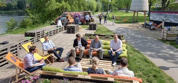Der Neckar soll an vielen Stellen mit unterschiedlicher Nutzung erlebbar sein, qualitativ aufgewertet werden und an möglichst vielen Abschnitten uferbegleitende attraktive Fuß- und Radwege anbieten. (Foto: Rothe) Menschen sitzen auf Holzpaletten am Flussufer.