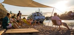 Menschen machen Yoga-Übungen an einem künstlichen Sandstrand am Neckar. 