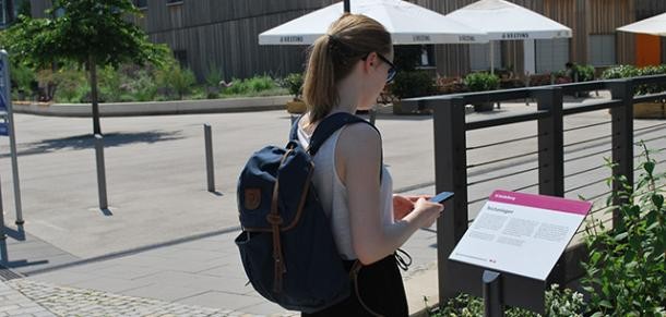 Frau steht vor Bahnstadtpfad-Schild