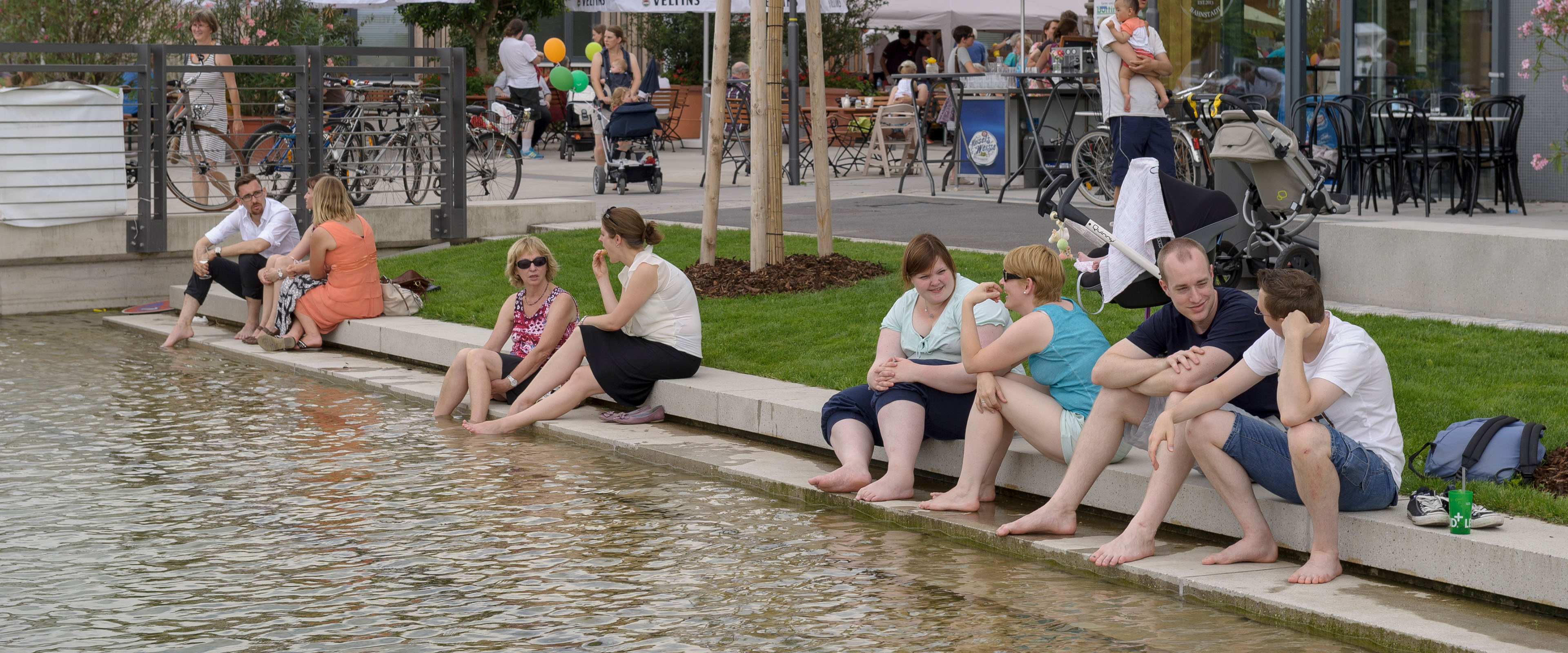 Menschen sitzen am Wasserbecken in der Bahnstadt