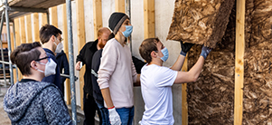 Mehrere Menschen arbeiten an einer Häuserdämmung. Sie tragen medizinische Masken.