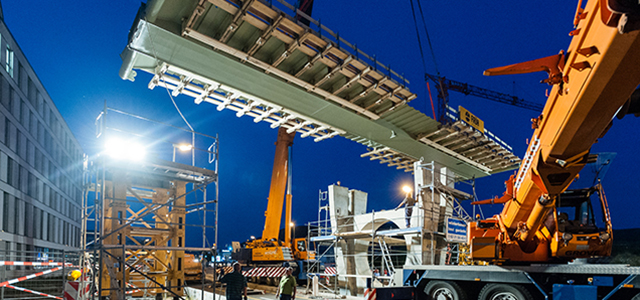 Brückenteile an einer Baustelle werden mit Kran eingehoben.