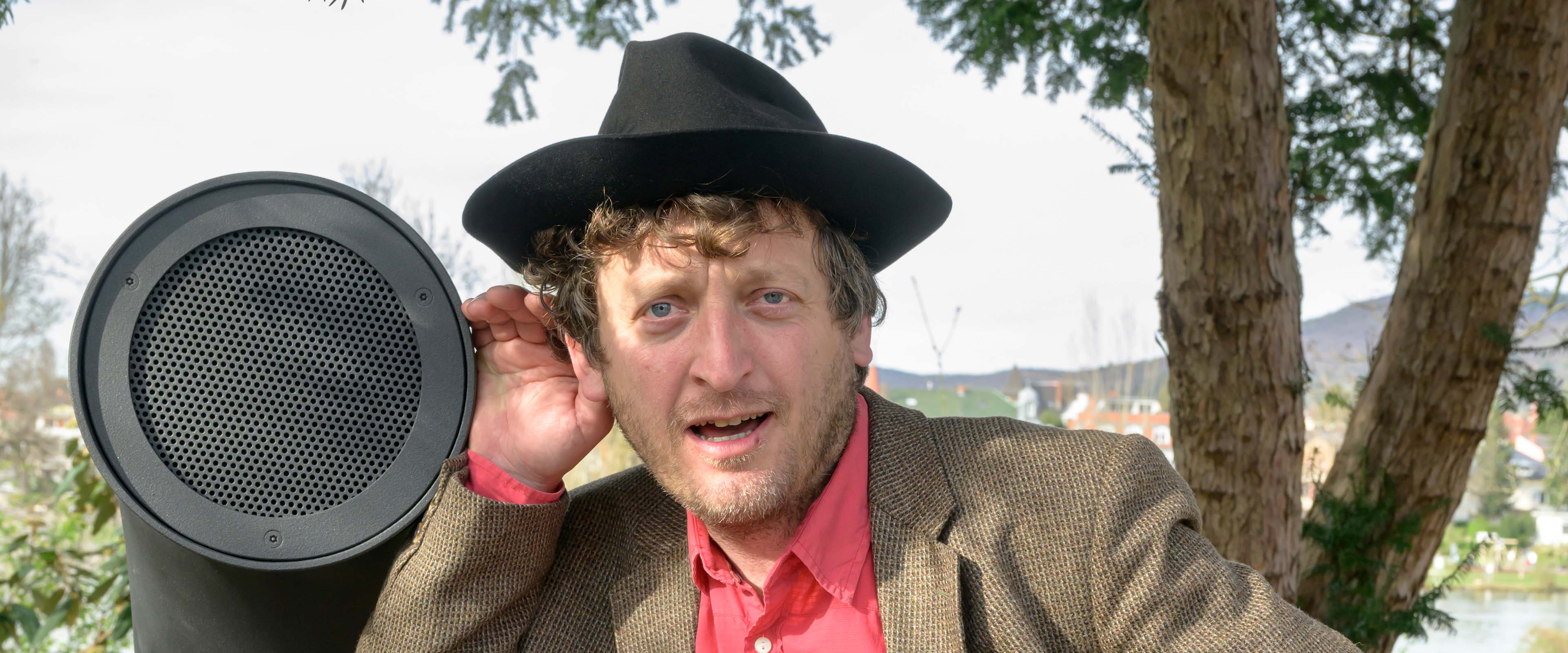 Erfinder Ondřej Kobza, ein Mann mit Hut, steht am Poesiomat und lauscht