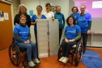 8 Personen, davon zwei im Rollstuhl stehen um eine aufgeklappte mobile Rampe 8 Personen, davon zwei im Rollstuhl stehen um eine aufgeklappte mobile Rampe