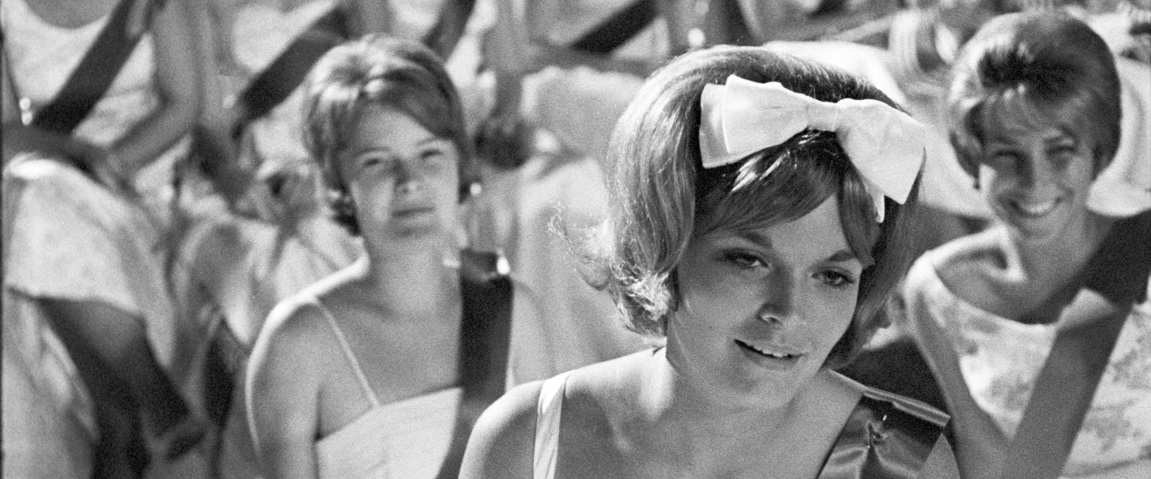 Schwarz-Weiß Fotografie - im Vordergrund Frau mit weißer Schleife